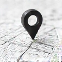 A detailed map pin icon pointing to a specific location on a minimalist map. The map shows city streets and a building outline. No text or symbols within the image.